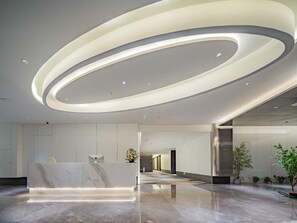 A modern reception area with a marble reception desk, recessed lighting, and potted plants. - Xian Jing - Scenery Hotel (Xi'an)