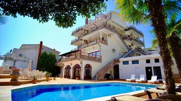 A hotel with a swimming pool, multiple balconies, and outdoor seating.