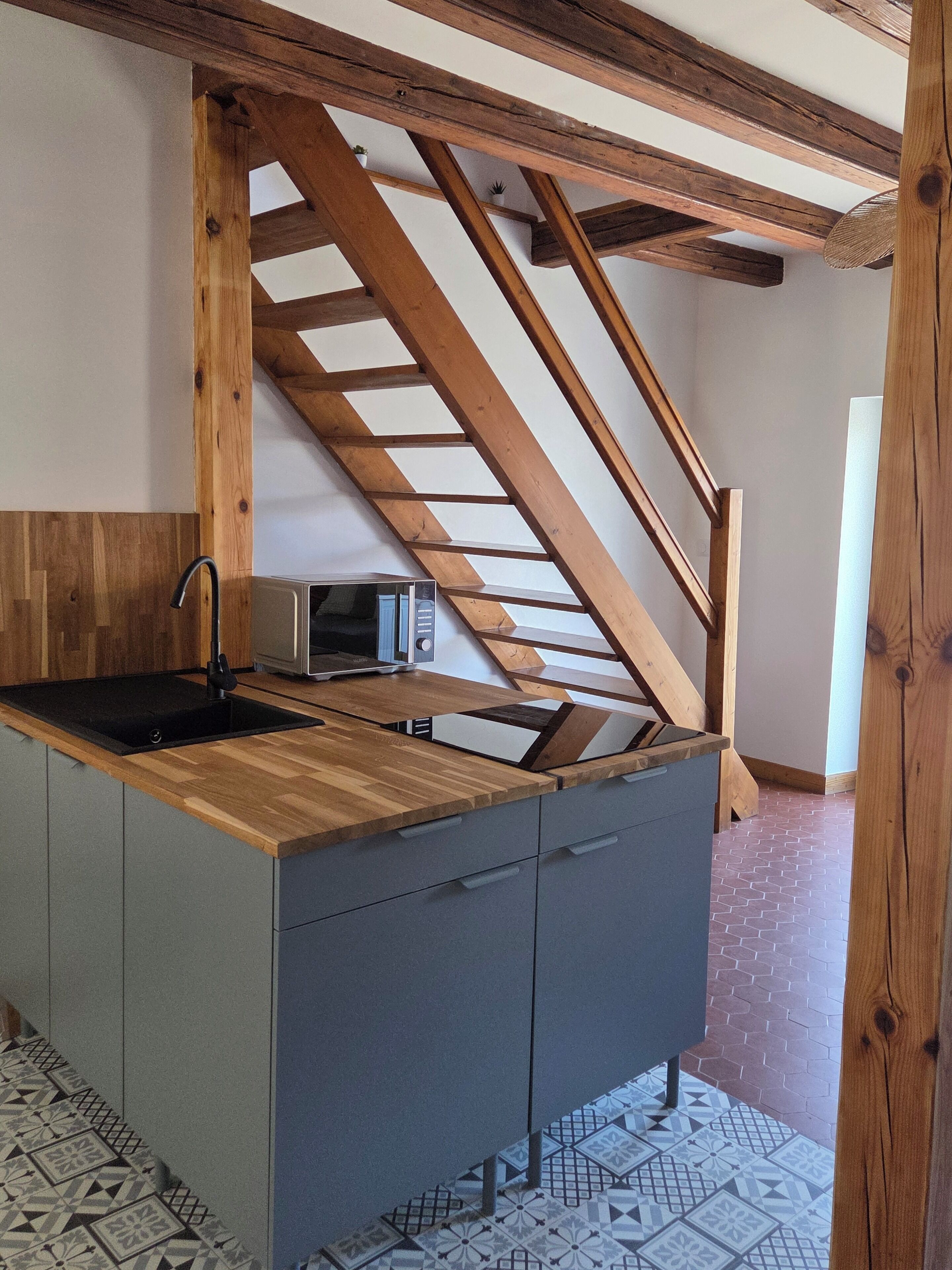 A kitchen with a wooden countertop, a sink, and a microwave.