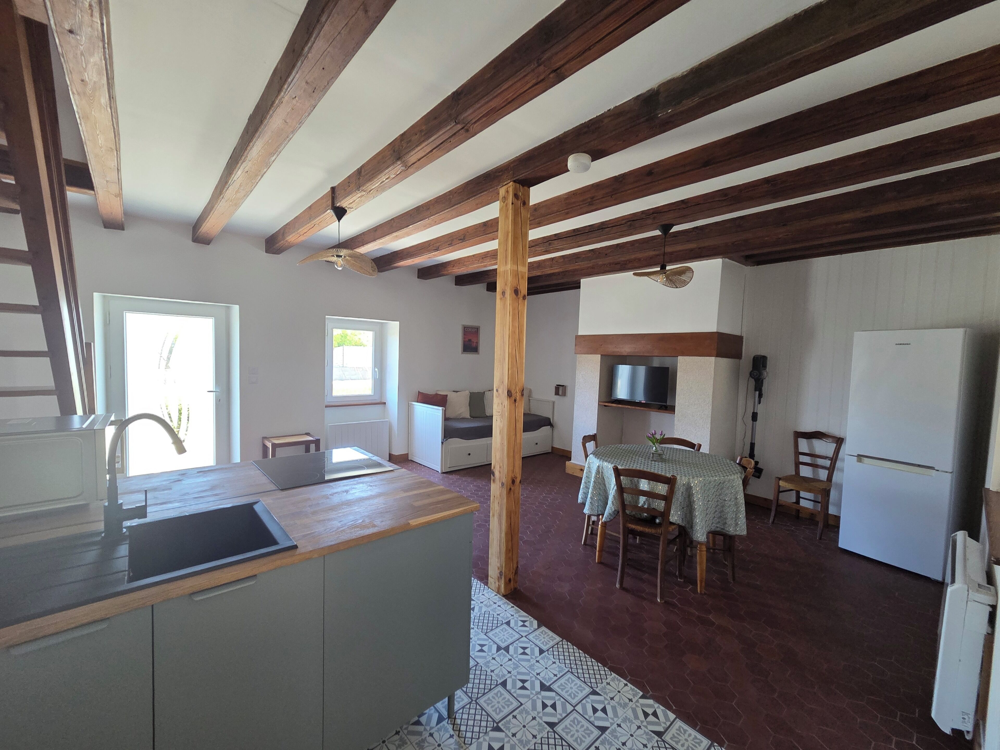 Een keuken met een houten plafond, een eethoek met een tafel en stoelen, en een koelkast.