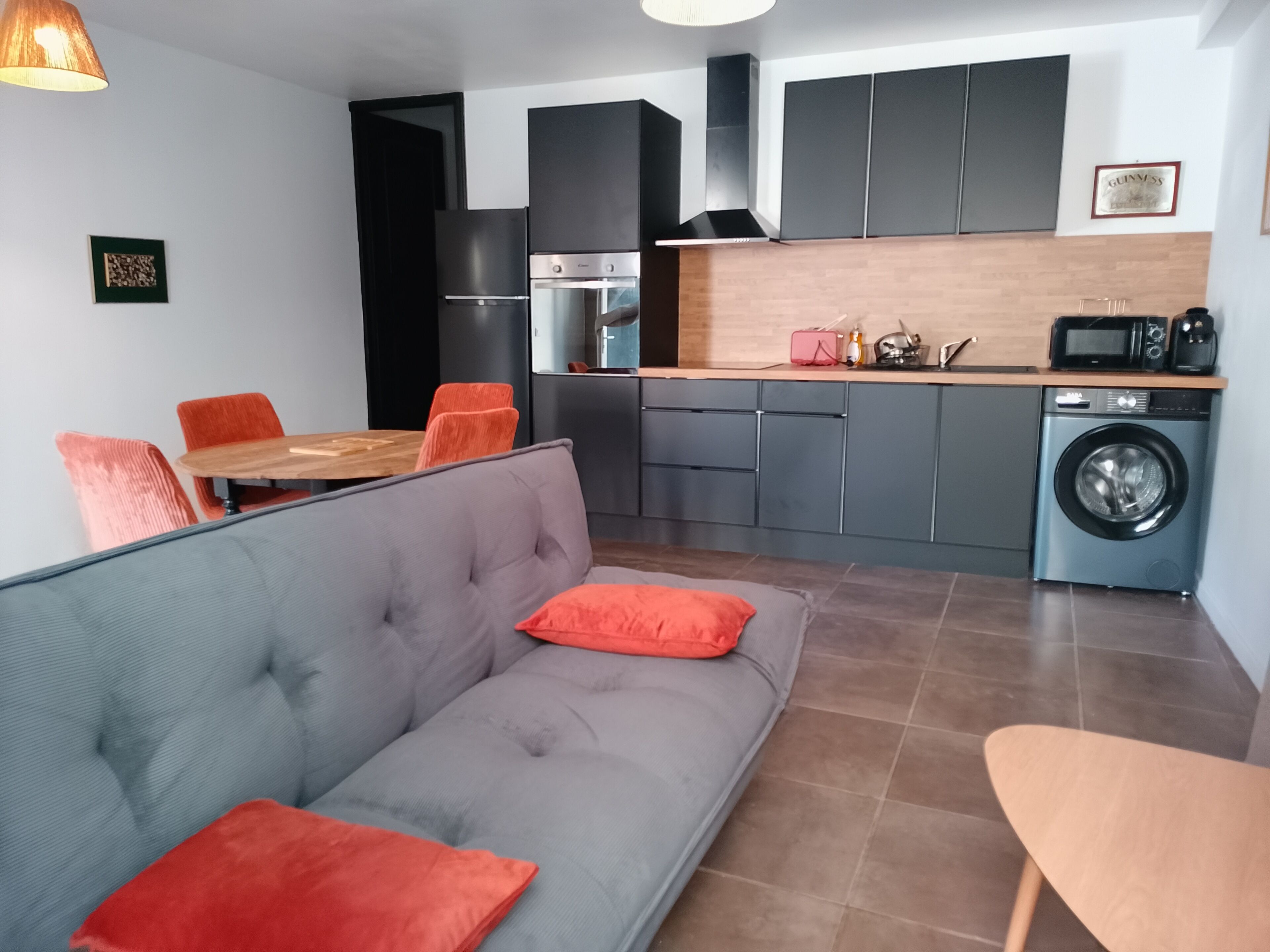 A modern kitchen with grey cabinets, a built-in oven, and a washing machine.