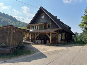 A two-story wooden house with a porch, a visible number '43' on the side, and a gravel driveway.