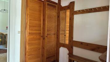 Une armoire en bois avec une porte miroir, un banc en bois et un mur blanc.