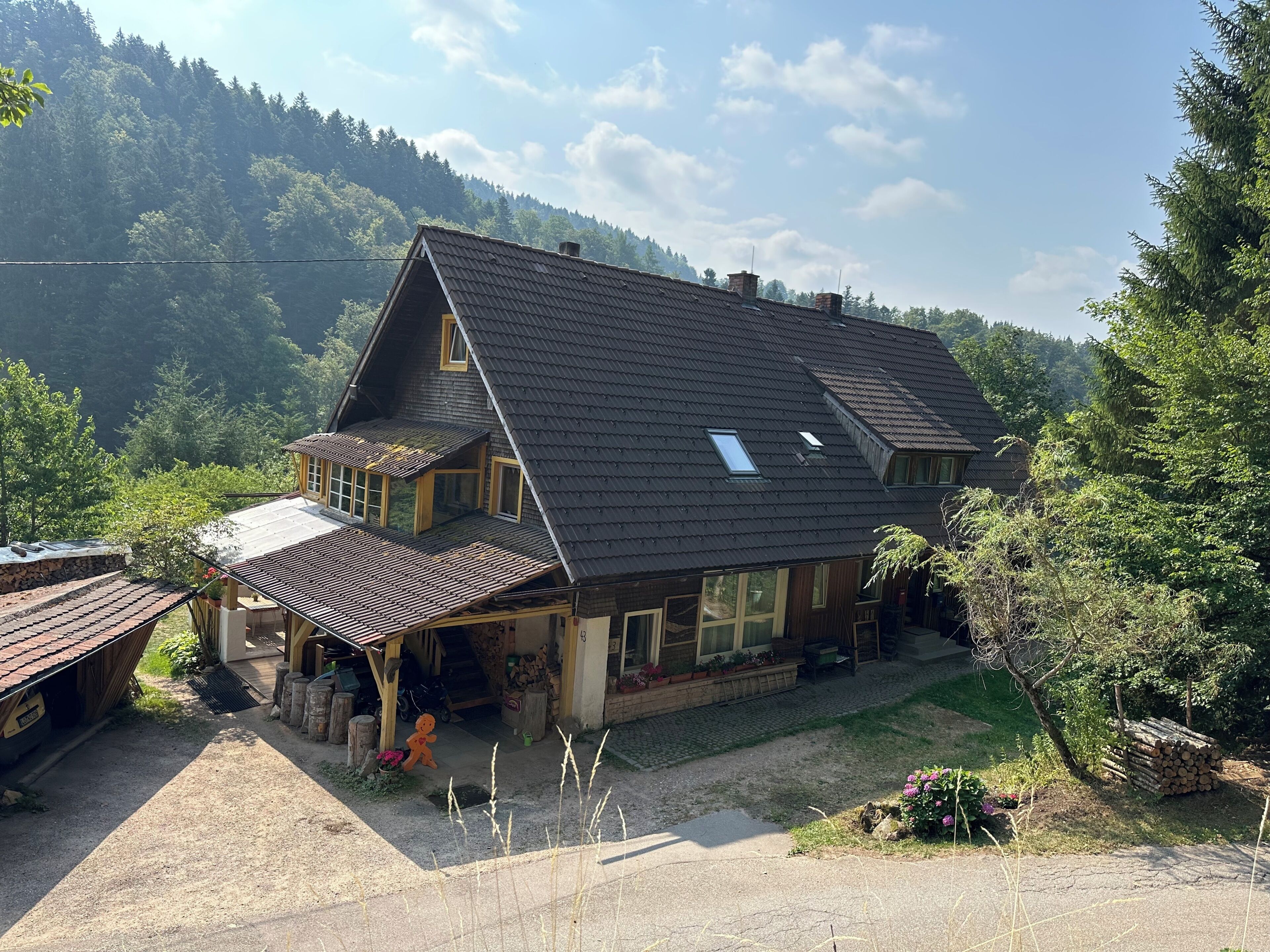 Ein zweigeschossiges Haus mit Satteldach, einer Veranda und einem kleinen Garten.
