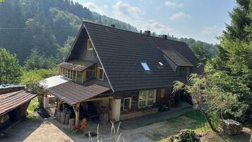 Ein zweigeschossiges Haus mit Satteldach, einer Veranda und einem kleinen Garten.
