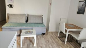 Una sala moderna con un sofá, una mesita y una mesita auxiliar de madera.