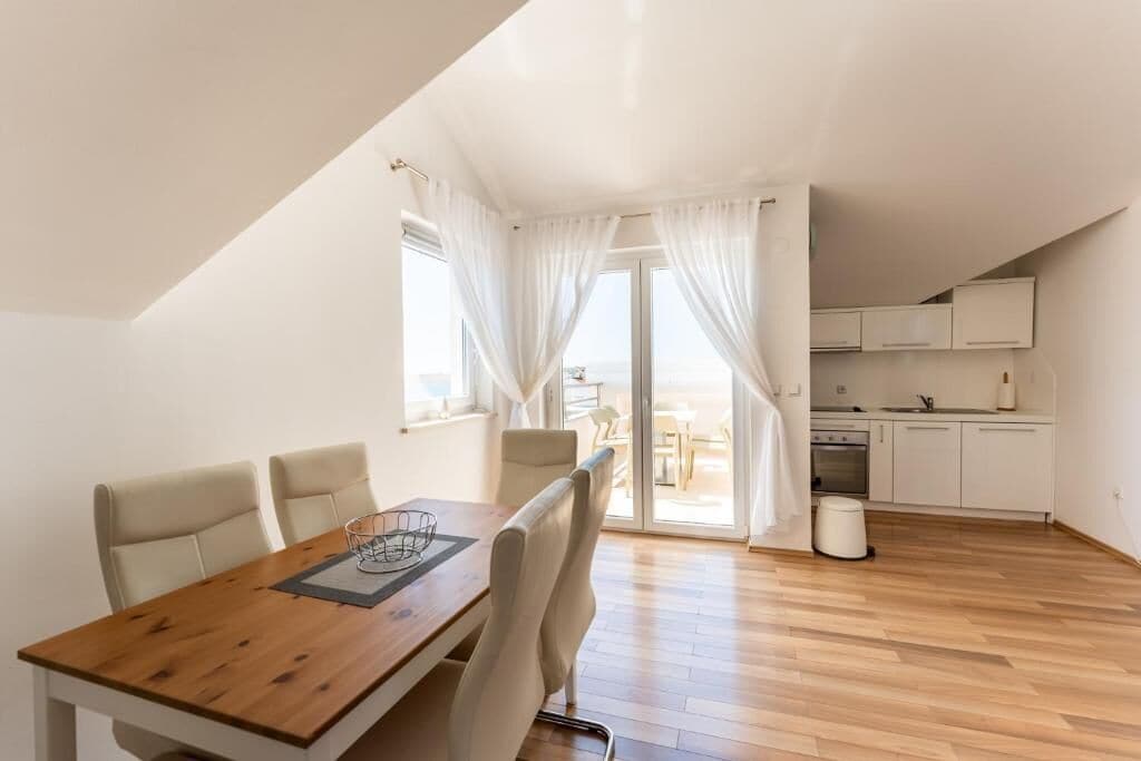 A modern kitchen with white cabinets and a dining area with a wooden table and chairs.