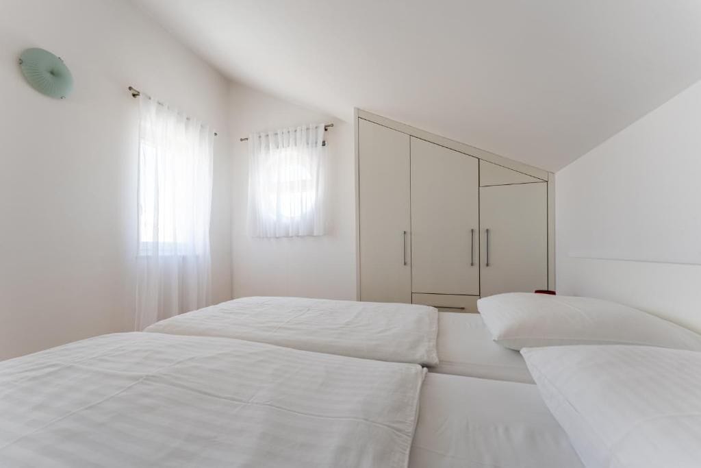Een slaapkamer met twee bedden, een kast en een raam met gordijnen.