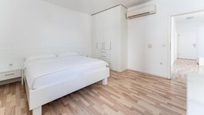 Ein Schlafzimmer mit einem Bett, einem Kleiderschrank, einem Nachttisch und einer Klimaanlage.