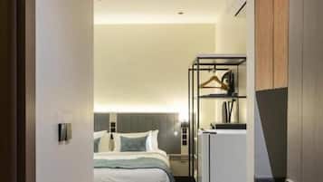 Quarto de hotel com uma cama, uma kitchenette e um banheiro visível através de uma porta aberta.