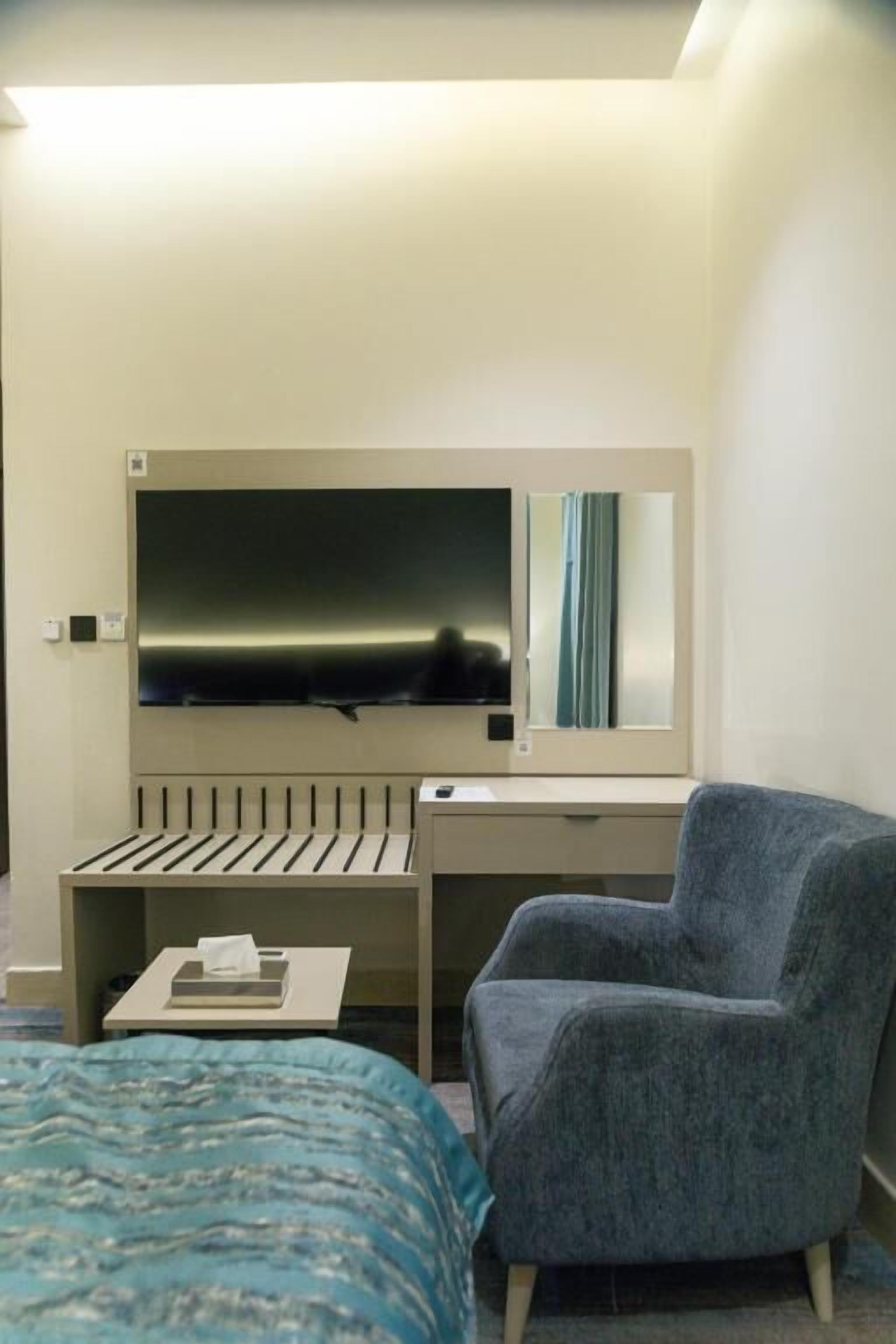 Une chambre d’hôtel avec un lit, un bureau, une chaise et un téléviseur.