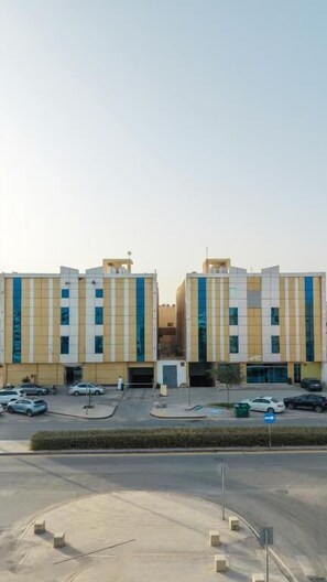 A modern building with a symmetrical facade, multiple windows, and a parking area in front. - HOLIDAY AL KHALEEJ HOTEL AL FALAH (AL RIYADH)