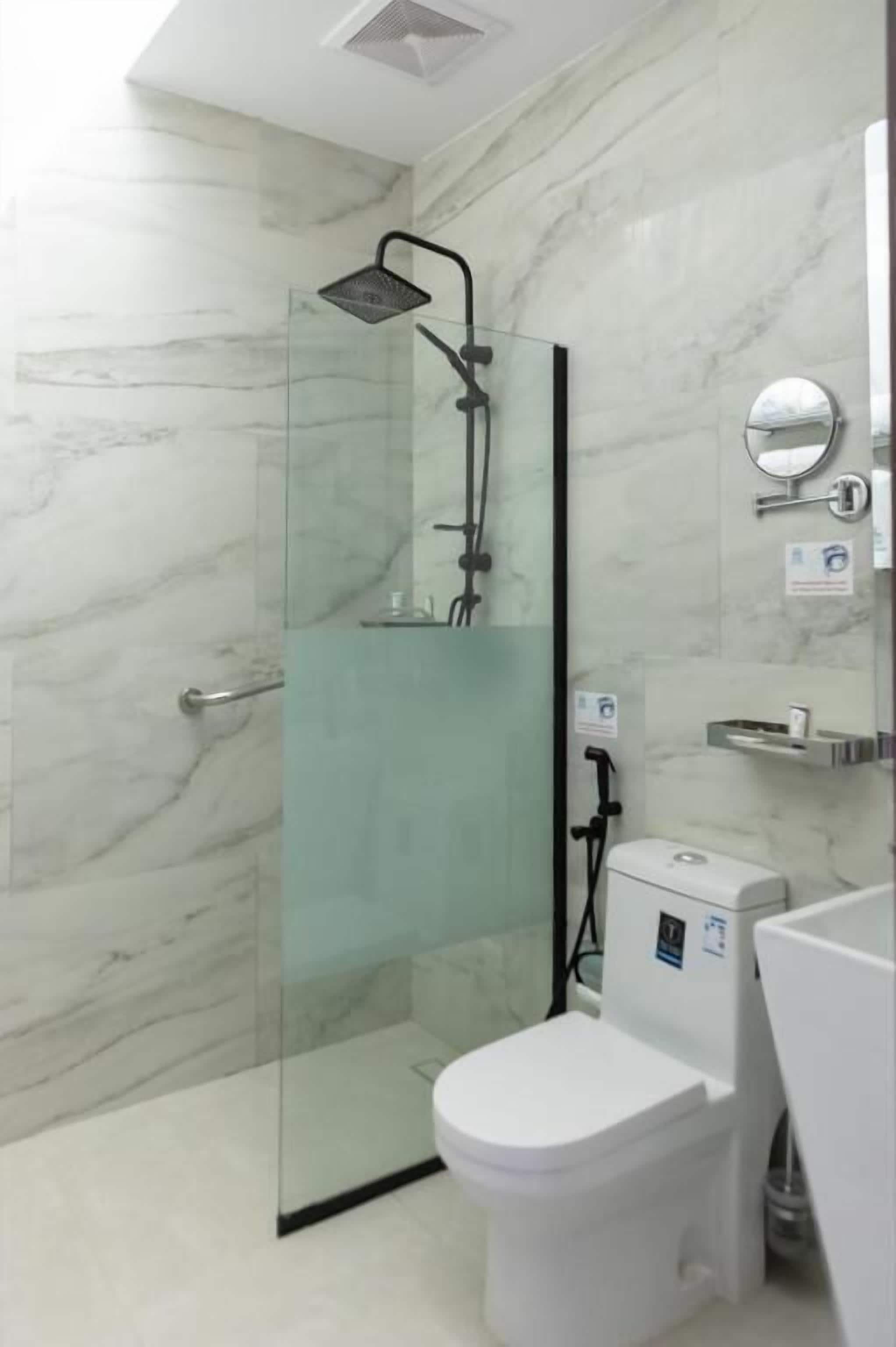 A modern bathroom with a glass-enclosed shower, a white toilet, and a marble wall.