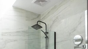 Un baño moderno con ducha de vidrio, inodoro blanco y pared de mármol.