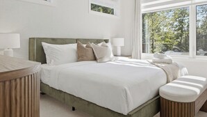 Una camera d'albergo moderna con un letto grande, comodini e vista sull'esterno.
