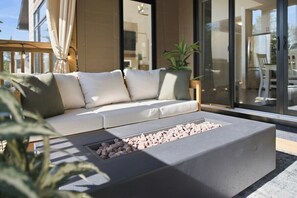 En modern utomhuslounge med en soffa och en inbyggd eldstad.