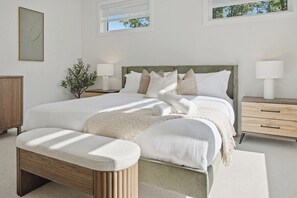 A bedroom with a large bed, bedside tables, a bench, and a potted plant. - LOB Wellness Retreat-Hot Tub-Sauna-Games-Fire Pit (Lake of Bays)