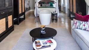 A hotel room with a canopy bed, a sitting area with a table, and a large bathtub. - Livingstone junior s (Livingstone)