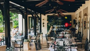 An outdoor dining area with tables set for a meal, featuring metal chairs and a ceiling fan. - Livingstone junior s (Livingstone)