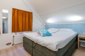 Un dormitorio con una cama individual, un radiador, una ventana con cortinas y una pared decorada.