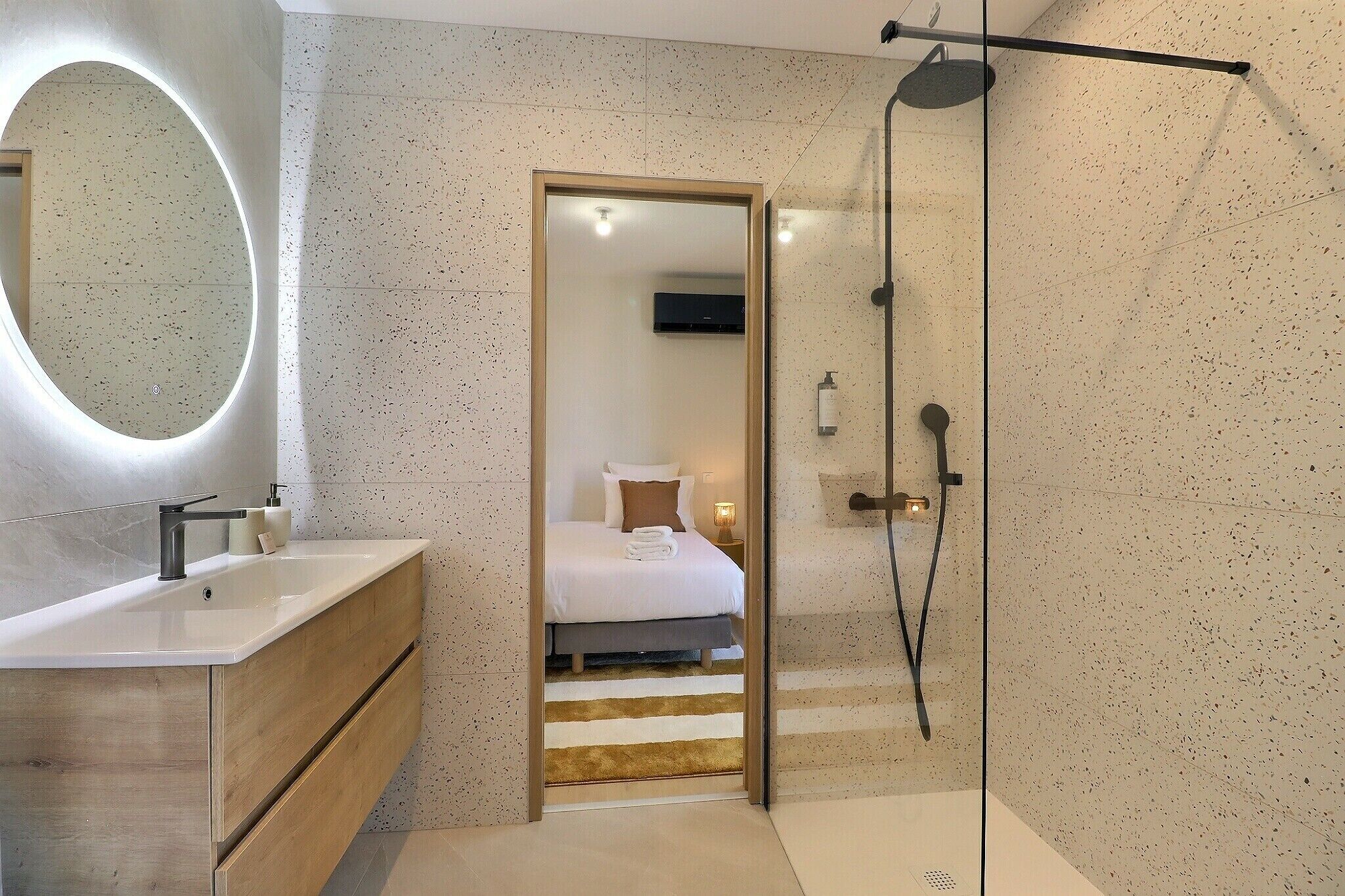 Une salle de bain moderne avec une douche, un lavabo et un miroir.