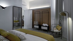 Quarto de hotel moderno com uma cama grande, área de estar com uma poltrona, guarda-roupa e escrivaninha.