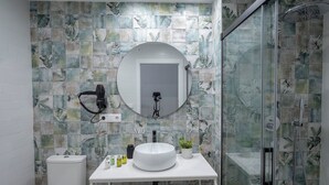 Uma casa de banho moderna com sanita, lavatório e chuveiro.