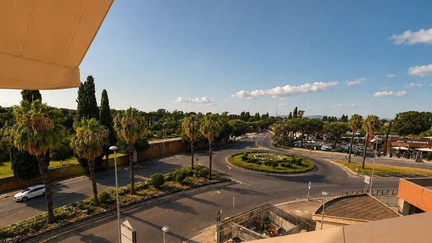 A roundabout with palm trees, a McDonald's restaurant, and a clear sky. - At Cherie's House! Nettuno! (Nettuno)