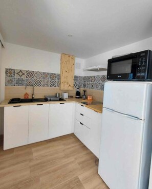 A kitchen with white cabinets, a microwave, and a sink. - Just like home: a cozy apartment with a local host (Talmont-Saint-Hilaire)