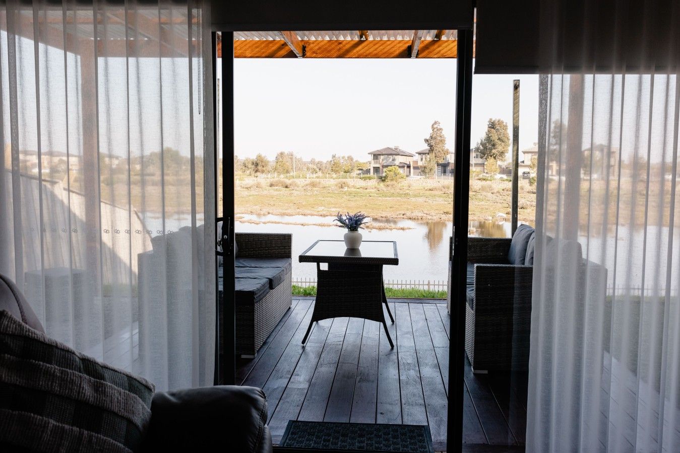An open deck with a table and chairs, overlooking a body of water and a distant landscape.