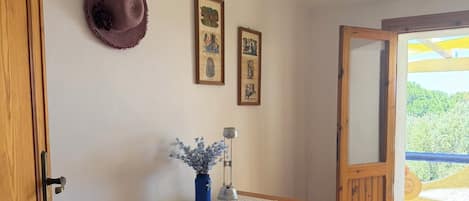 Escritorio de madera con un florero de flores secas, una lámpara y dos cuadros en la pared.