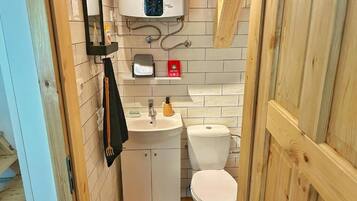 Baño pequeño con inodoro, lavamanos y un calentador de pared.