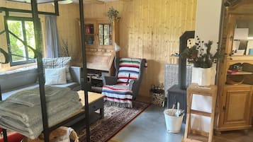 Une pièce chaleureuse et accueillante, avec un lit, un canapé, un fauteuil coloré, une armoire en bois et une cheminée.