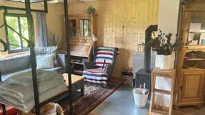 Una habitación acogedora con cama, sofá, sillón colorido, aparador de madera y chimenea.