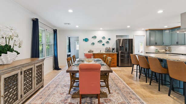 A modern kitchen with a central island, stainless steel appliances, and a dining area with a patterned rug. - Game Room | Open Living Space | Large Kitchen | Sunroom | Fenced Backyard | Fire Pit (St. Simons Island)