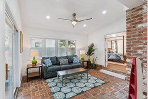 A living room with a sofa, coffee table, and a patterned rug. - Game Room | Open Living Space | Large Kitchen | Sunroom | Fenced Backyard | Fire Pit (St. Simons Island)