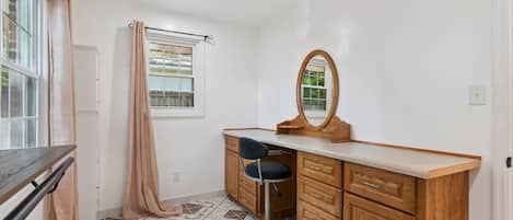 A bathroom with a vanity, a mirror, a shower curtain, and a window.
