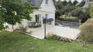 Una casa con patio, tavolo e sedie, e un recinto bianco.
