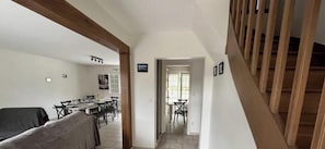 A spacious living area with a dining table and chairs, a covered sofa, and a staircase leading to an upper floor. - The Gîte des Pélus, perfect for a getaway in the countryside, less than 10 minutes from Tours. (Rochecorbon)