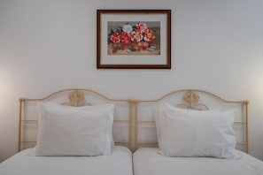 A double bed with white bedding and a wooden headboard, a framed floral painting above it, and a plain wall. - Quinta de S. Caetano- S. Miguel-Açores (Ponta Delgada)