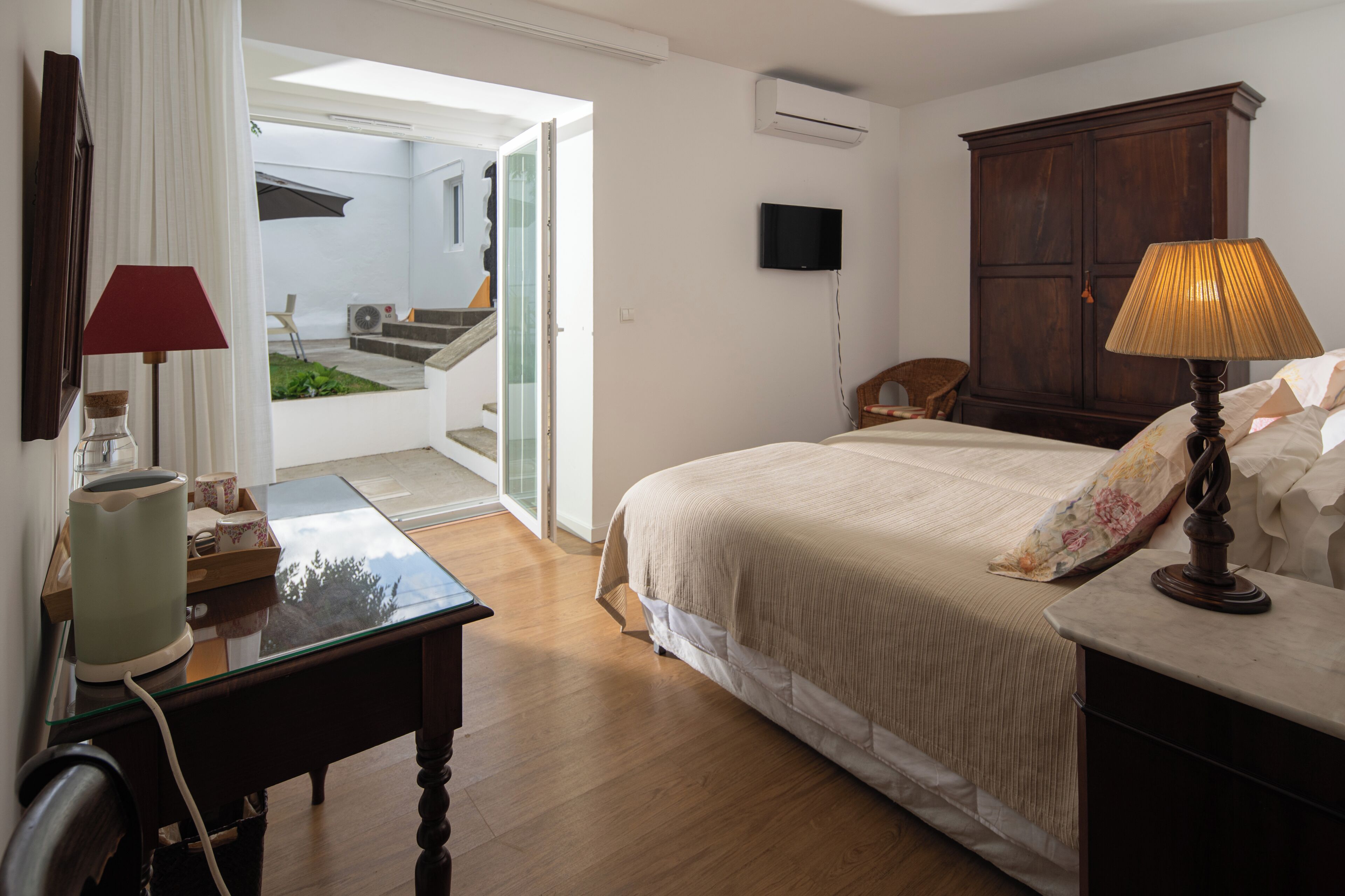 Une chambre à coucher avec un lit, un bureau, une chaise, une lampe et un téléviseur.