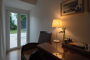 A room with a wooden desk, a chair, a lamp, a framed picture on the wall, and a view through a glass door. - Quinta de S. Caetano- S. Miguel-Açores (Ponta Delgada)
