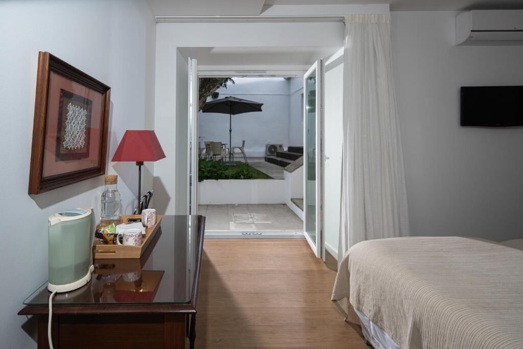 Une chambre d’hôtel avec un lit, un bureau doté d’une lampe, un tableau encadré et une vue sur un patio extérieur.