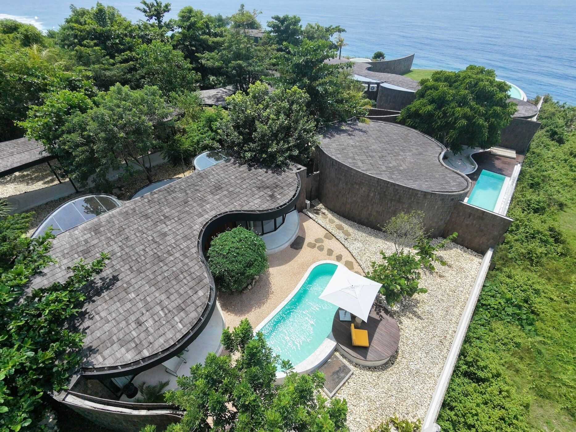 Ein modernes Resort mit Pool, mehreren Gebäuden und Blick auf den Ozean.