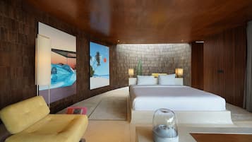 Una habitación de hotel moderna con una cama grande, una zona de estar y obras de arte en las paredes.