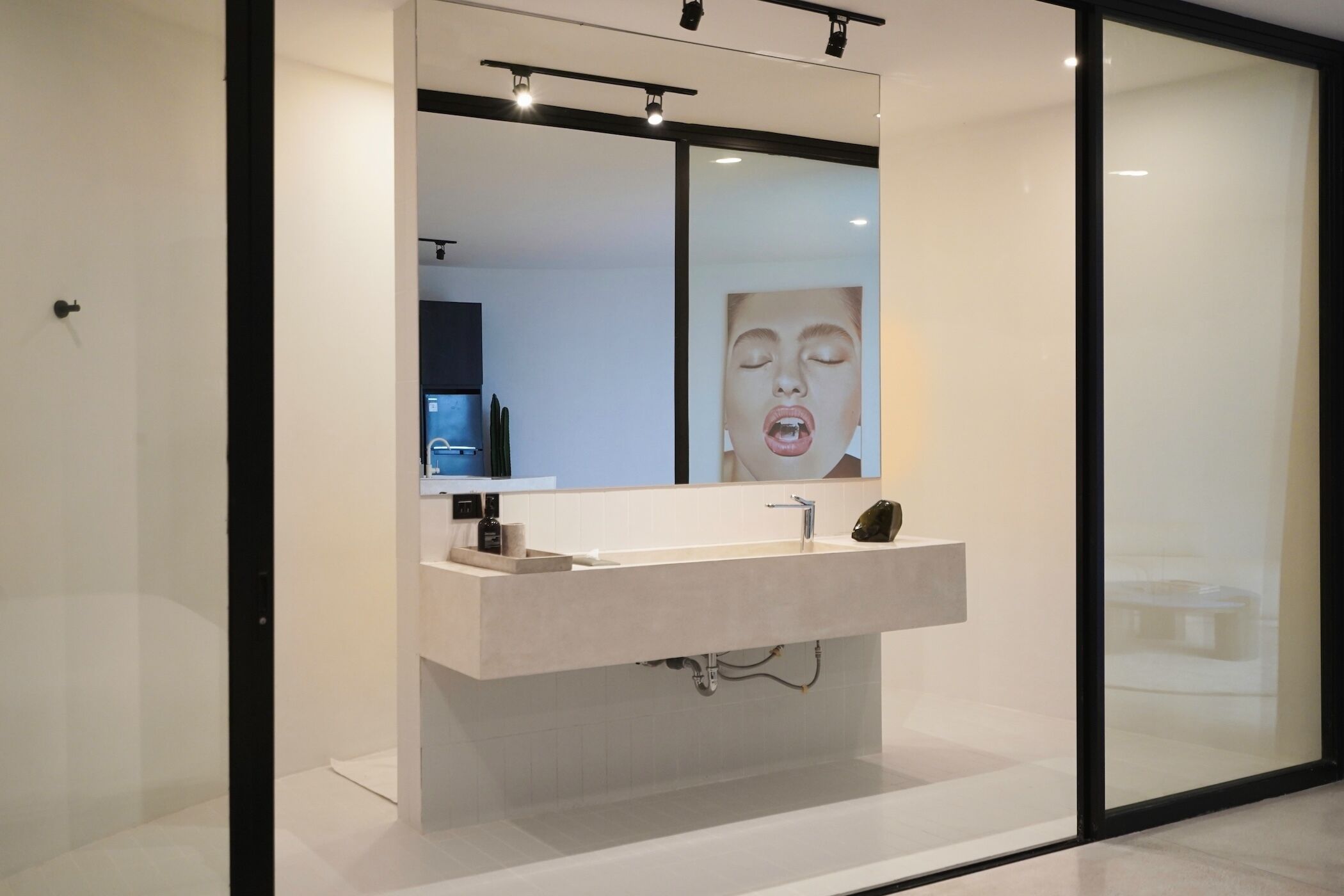 Une salle de bain moderne avec un grand miroir, un lavabo et un espace douche.