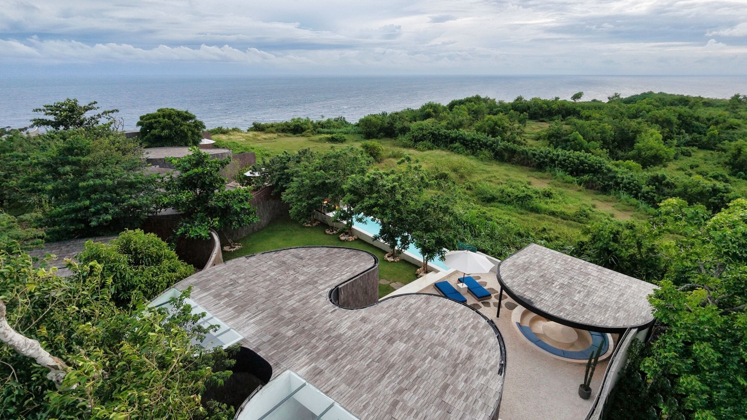 A rooftop with a pool, lounge chairs, and a view of the ocean.
