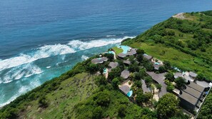 A coastal property with a swimming pool, multiple buildings, and lush greenery.