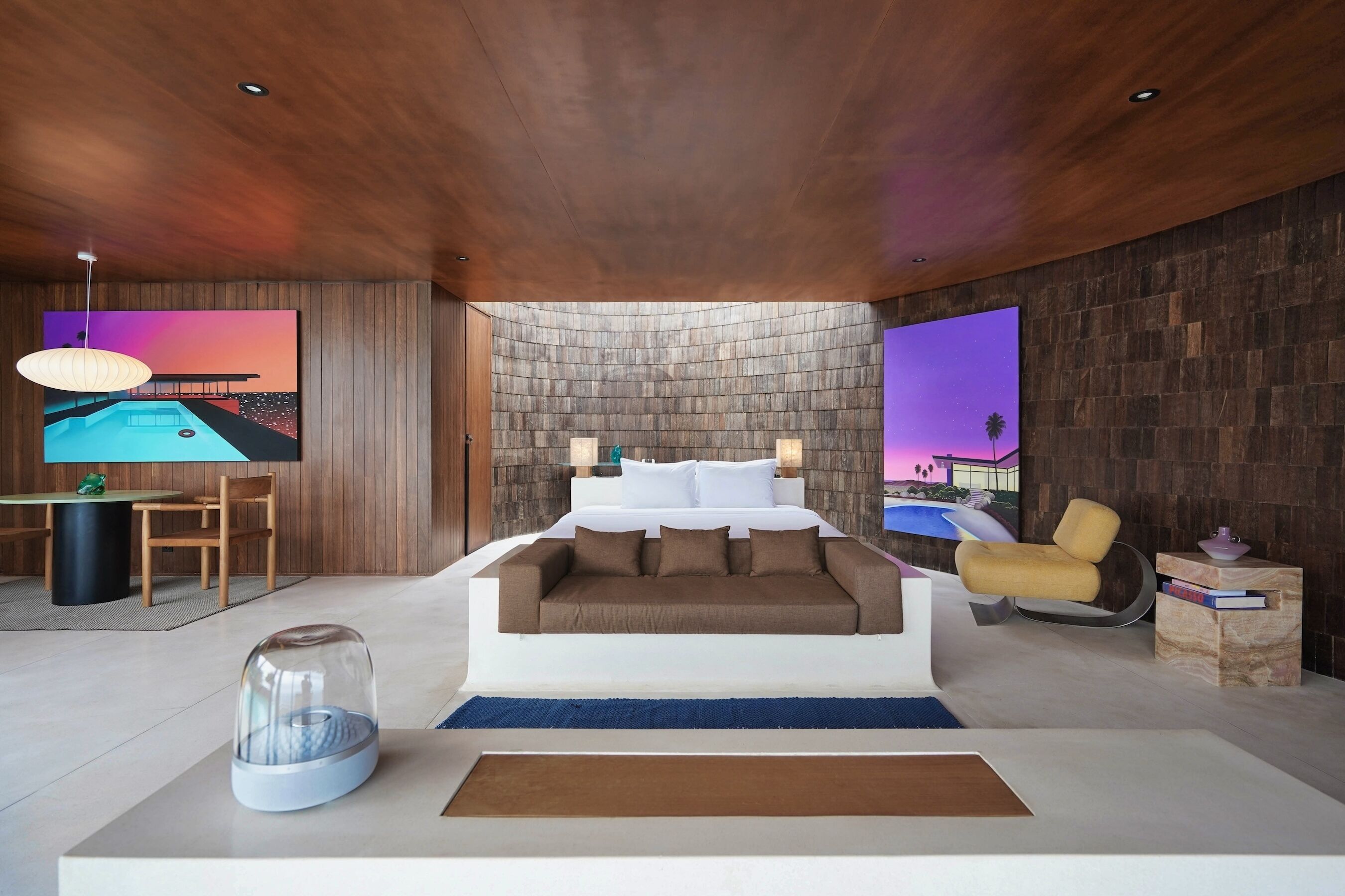 A modern bedroom with a large bed, a TV, and artwork on the walls.