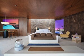 Un dormitorio moderno con una cama grande, televisión y obras de arte en las paredes.